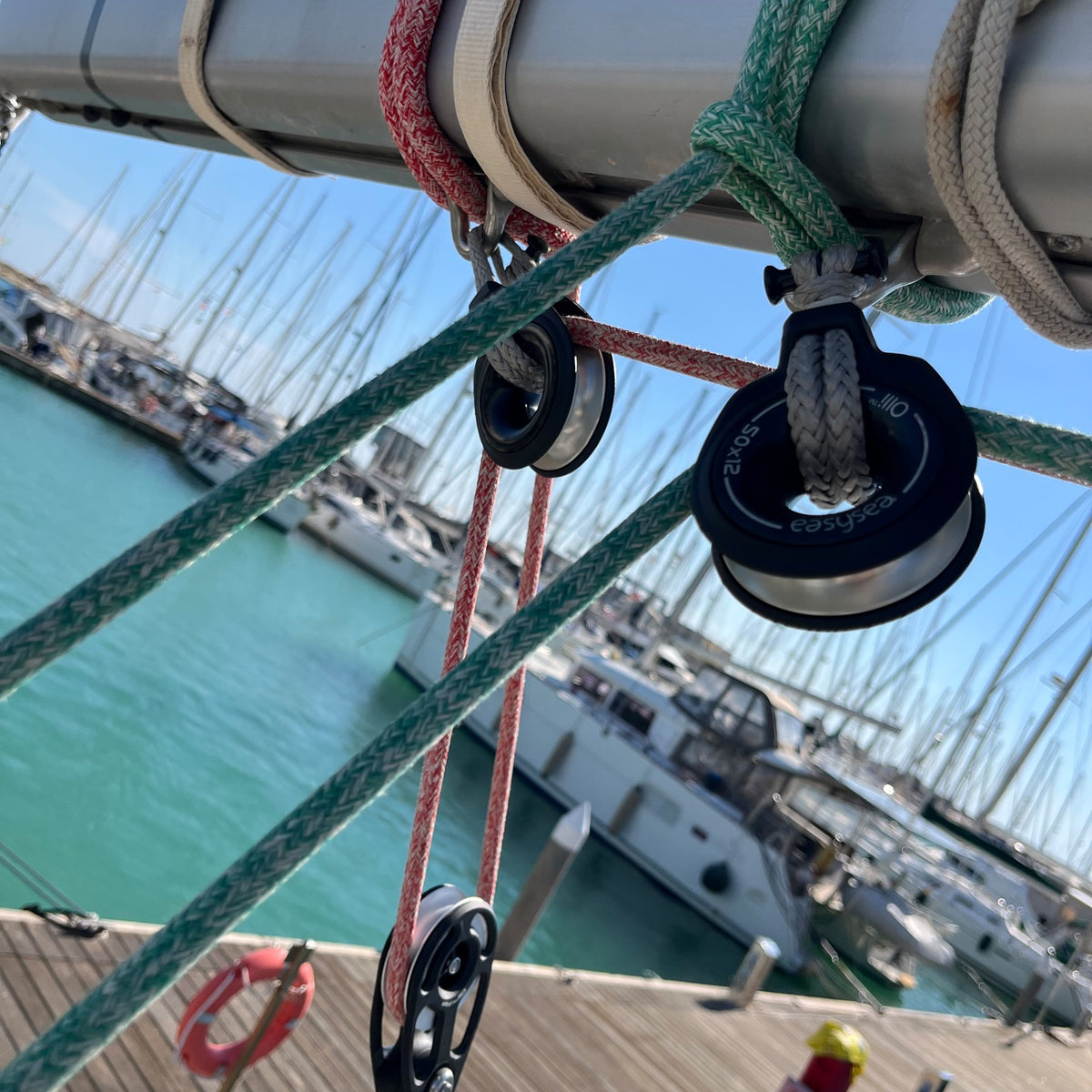 Two Olli snatch blocks on the boom and an Olli Flex HL block below, sheets running through, sailboat in a marina